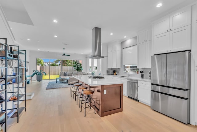 831 E 26th St, Houston, TX 77009 - kitchen featuring appliances with stainless steel finishes, extractor fan, a kitchen island, open floor plan, and white cabinets