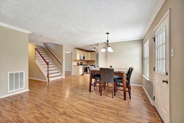 4235 Park Ridge Dr, Pasadena, TX 77504 - dining space featuring a chandelier, a textured ceiling, light wood-type flooring, ornamental molding, and stairs