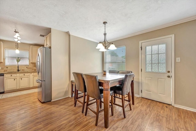 4235 Park Ridge Dr, Pasadena, TX 77504 - dining room featuring light wood-type flooring, a chandelier, healthy amount of natural light, a textured ceiling, and crown molding