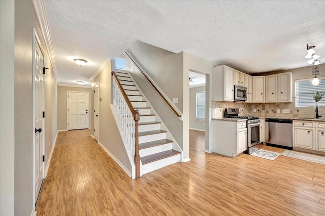 4235 Park Ridge Dr, Pasadena, TX 77504 - kitchen featuring stainless steel appliances, a textured ceiling, light wood finished floors, tasteful backsplash, and healthy amount of natural light