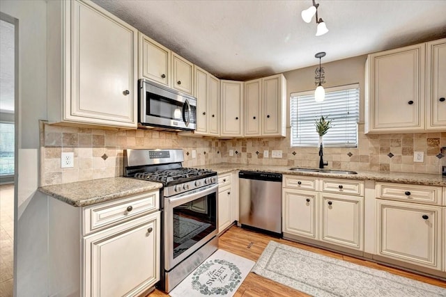 4235 Park Ridge Dr, Pasadena, TX 77504 - kitchen with stainless steel appliances, cream cabinets, hanging light fixtures, and backsplash