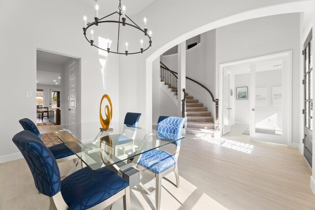 454 Patina Dr, Montgomery, TX 77316 - dining area featuring a chandelier, stairs, arched walkways, light wood-type flooring, and baseboards