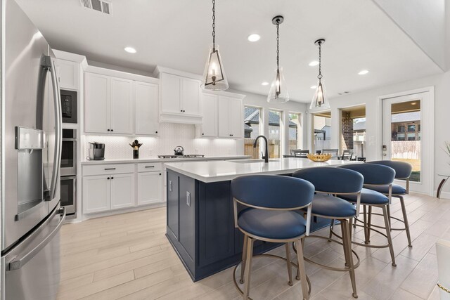 454 Patina Dr, Montgomery, TX 77316 - kitchen featuring stainless steel appliances, a sink, a kitchen breakfast bar, tasteful backsplash, and light countertops