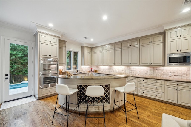 5710 Logan Ln, Houston, TX 77007 - kitchen with stainless steel appliances, crown molding, a kitchen breakfast bar, backsplash, and dark stone countertops