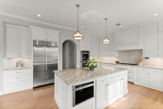 1705 Michigan St, Houston, TX 77006 - kitchen with stainless steel appliances, arched walkways, tasteful backsplash, white cabinets, and ornamental molding
