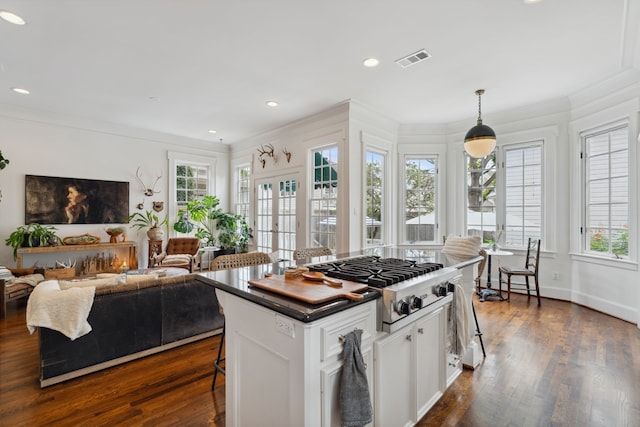 613 E 18th St, Houston, TX 77008 - kitchen featuring stainless steel gas stovetop, a kitchen breakfast bar, ornamental molding, white cabinetry, and dark wood-style floors