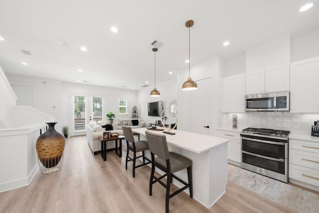 1503 Evelyn St, Houston, TX 77009 - kitchen with stainless steel appliances, light wood-style flooring, decorative backsplash, a breakfast bar, and open floor plan