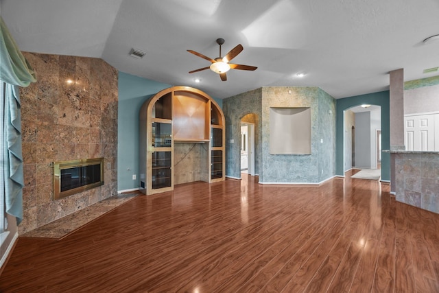 2723 Shelby Dr, Pearland, TX 77584 - unfurnished living room with a ceiling fan, a fireplace, wood finished floors, arched walkways, and lofted ceiling