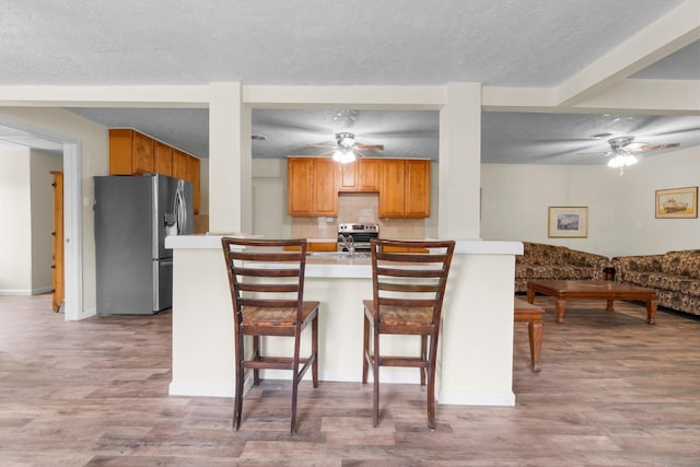 168 Bay Haven Blvd, Livingston, TX 77351 - kitchen featuring appliances with stainless steel finishes, a ceiling fan, light wood finished floors, a kitchen bar, and a textured ceiling