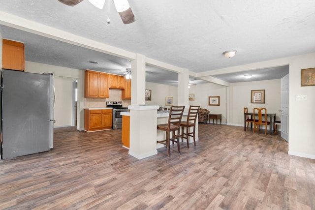 168 Bay Haven Blvd, Livingston, TX 77351 - kitchen featuring stainless steel appliances, ceiling fan, dark wood-style flooring, light countertops, and a kitchen bar