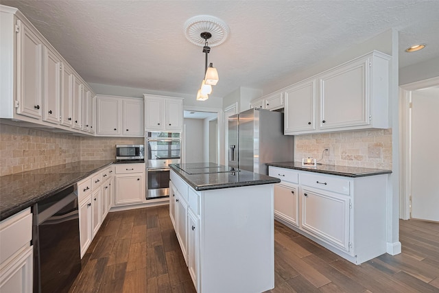 3406 Mesquite Dr, Sugar Land, TX 77479 - kitchen featuring appliances with stainless steel finishes, dark wood-style floors, a kitchen island, white cabinetry, and a textured ceiling