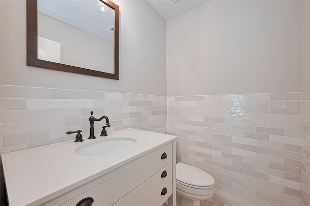 3406 Mesquite Dr, Sugar Land, TX 77479 - half bathroom featuring tile walls, toilet, vanity, wainscoting, and a textured ceiling