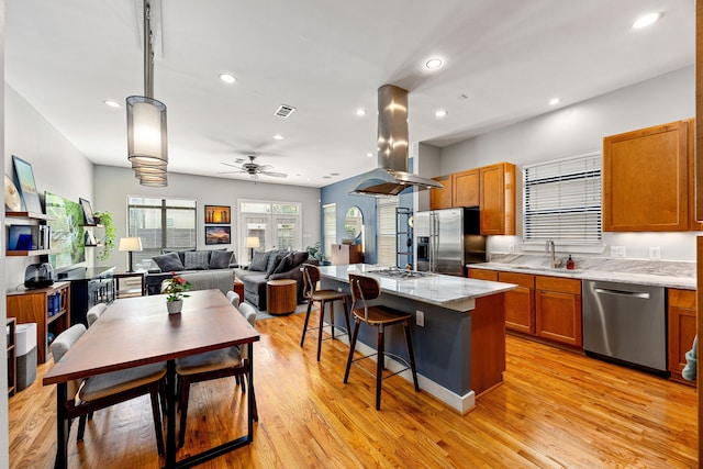 1410 Knox St, Houston, TX 77007 - kitchen featuring stainless steel appliances, island exhaust hood, a sink, a ceiling fan, and brown cabinetry