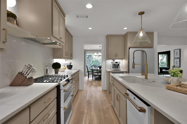 10090 Valley Dr S, Willis, TX 77318 - kitchen featuring white appliances, light wood-style flooring, a sink, hanging light fixtures, and light stone countertops