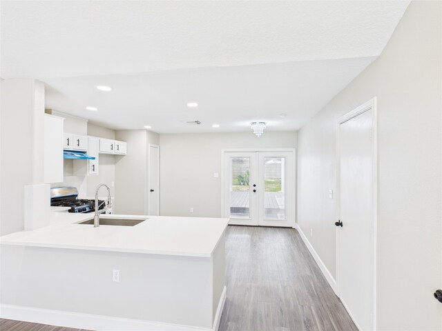 3219 Ricewood Dr, Porter, TX 77365 - kitchen with a sink, gas stove, a peninsula, under cabinet range hood, and white cabinets