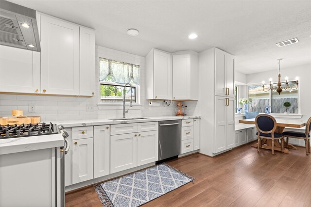 10618 Cranbrook Rd, Houston, TX 77042 - kitchen featuring stainless steel appliances, wall chimney range hood, a sink, dark wood-style floors, and healthy amount of natural light