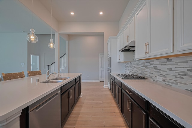 1718 Pepper Grove Ln, Katy, TX 77494 - kitchen with appliances with stainless steel finishes, under cabinet range hood, a sink, light countertops, and white cabinets