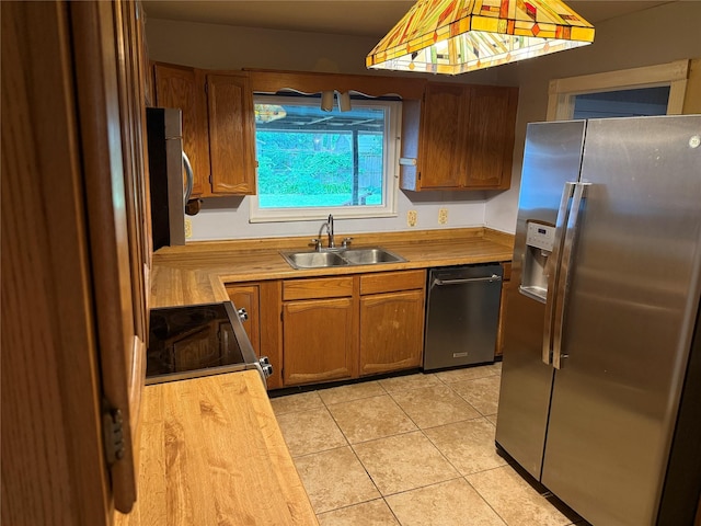 1707 Key St, Waller, TX 77484 - kitchen with appliances with stainless steel finishes, a sink, light tile patterned floors, butcher block countertops, and brown cabinetry