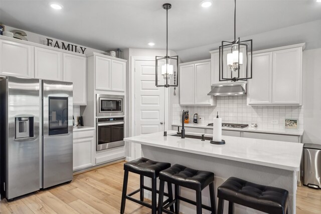 512 Highland Thicket Dr, Montgomery, TX 77316 - kitchen featuring appliances with stainless steel finishes, under cabinet range hood, backsplash, light countertops, and white cabinets