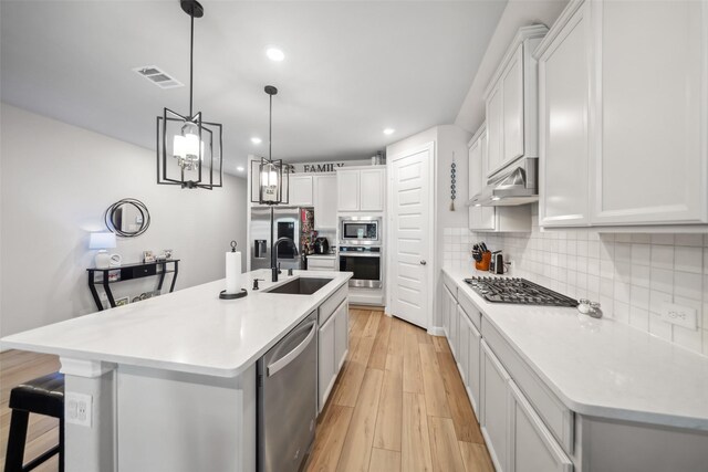 512 Highland Thicket Dr, Montgomery, TX 77316 - kitchen with appliances with stainless steel finishes, under cabinet range hood, a sink, decorative backsplash, and light countertops