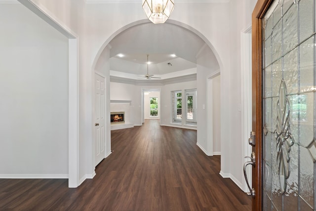 110 Canterbury Green Dr, Conroe, TX 77356 - foyer featuring ceiling fan, dark wood-style floors, a tray ceiling, a lit fireplace, and arched walkways
