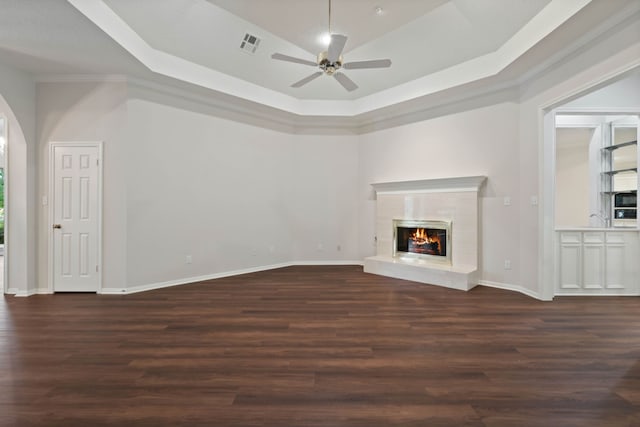110 Canterbury Green Dr, Conroe, TX 77356 - unfurnished living room featuring wood finished floors, a ceiling fan, a glass covered fireplace, arched walkways, and a raised ceiling