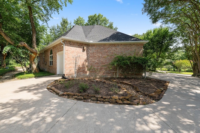 110 Canterbury Green Dr, Conroe, TX 77356 - view of side of property featuring brick siding, an attached garage, roof with shingles, and driveway