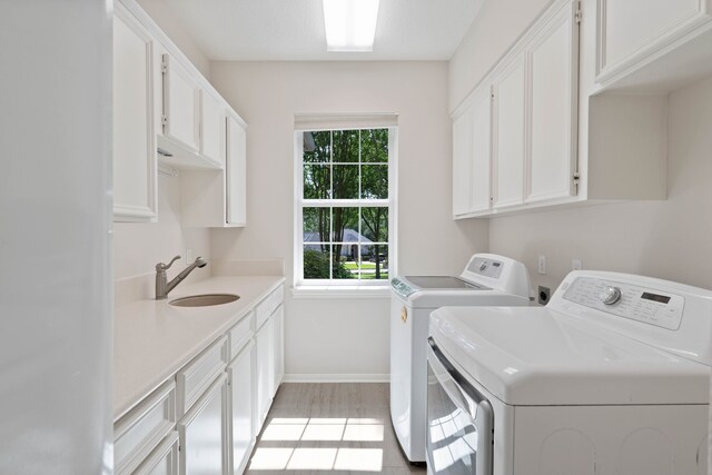 110 Canterbury Green Dr, Conroe, TX 77356 - laundry area featuring washer and dryer, cabinet space, and light wood finished floors