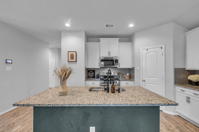 2322 Strong Horse Dr, Conroe, TX 77301 - kitchen with appliances with stainless steel finishes, a sink, light wood-type flooring, light stone countertops, and recessed lighting