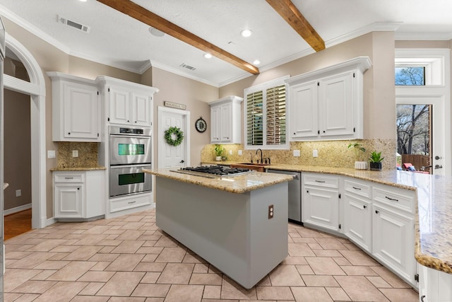 31026 Johlke Rd, Magnolia, TX 77355 - kitchen featuring a sink, stainless steel appliances, white cabinets, beam ceiling, and decorative backsplash