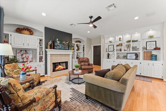 31026 Johlke Rd, Magnolia, TX 77355 - living room with built in shelves, a ceiling fan, light wood finished floors, a tiled fireplace, and recessed lighting
