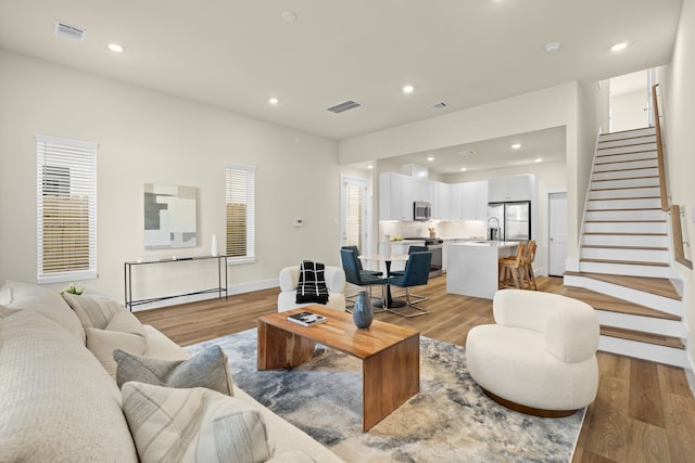5626 Bertellis Ln, Houston, TX 77091 - living room featuring stairs, light wood finished floors, baseboards, and recessed lighting