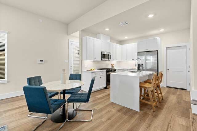 5626 Bertellis Ln, Houston, TX 77091 - kitchen with stainless steel appliances, tasteful backsplash, light wood finished floors, white cabinets, and light countertops