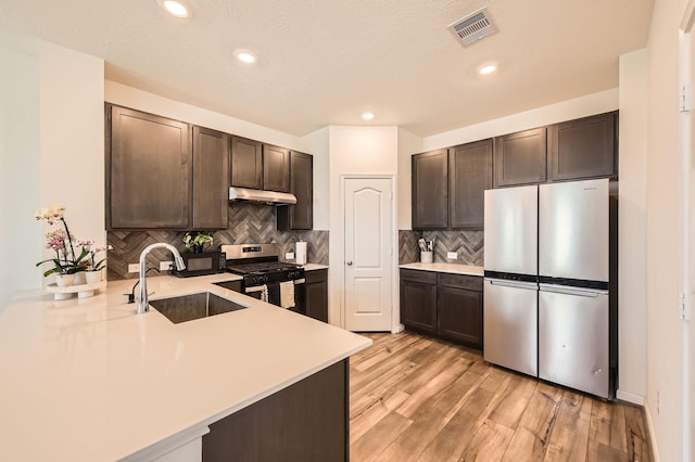 8126 Coco Bluff Dr, Cypress, TX 77433 - kitchen featuring appliances with stainless steel finishes, a sink, dark brown cabinetry, light countertops, and under cabinet range hood