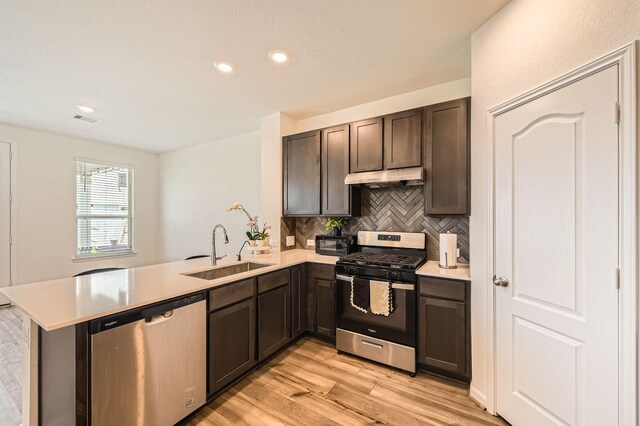 8126 Coco Bluff Dr, Cypress, TX 77433 - kitchen with appliances with stainless steel finishes, a sink, under cabinet range hood, a peninsula, and light wood-type flooring