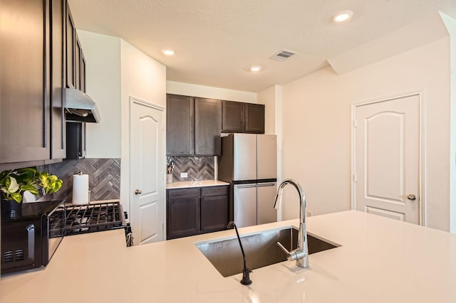 8126 Coco Bluff Dr, Cypress, TX 77433 - kitchen featuring freestanding refrigerator, under cabinet range hood, a sink, dark brown cabinetry, and tasteful backsplash