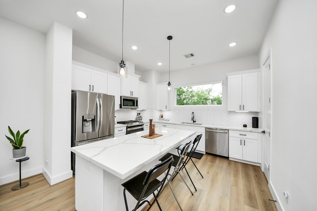 3022 Live Oak St, Houston, TX 77004 - kitchen featuring appliances with stainless steel finishes, tasteful backsplash, light wood-type flooring, a kitchen island, and recessed lighting
