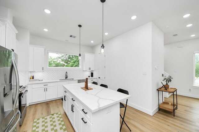3022 Live Oak St, Houston, TX 77004 - kitchen with appliances with stainless steel finishes, a sink, a breakfast bar area, decorative backsplash, and light wood-style flooring