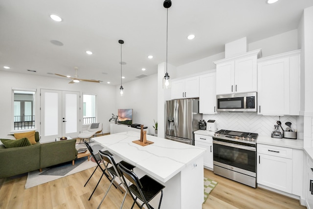 3022 Live Oak St, Houston, TX 77004 - kitchen featuring stainless steel appliances, open floor plan, a center island, tasteful backsplash, and white cabinets