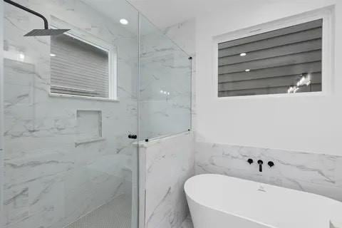 3022 Live Oak St, Houston, TX 77004 - bathroom featuring a marble finish shower, a soaking tub, and tile walls