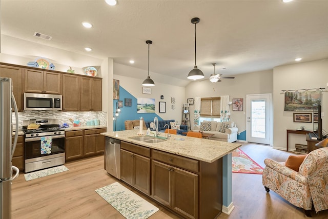 999 Arbor Gln, Conroe, TX 77303 - kitchen featuring appliances with stainless steel finishes, a sink, open floor plan, decorative backsplash, and a ceiling fan