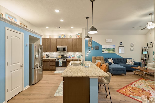 999 Arbor Gln, Conroe, TX 77303 - kitchen with stainless steel appliances, a sink, open floor plan, a breakfast bar, and brown cabinets