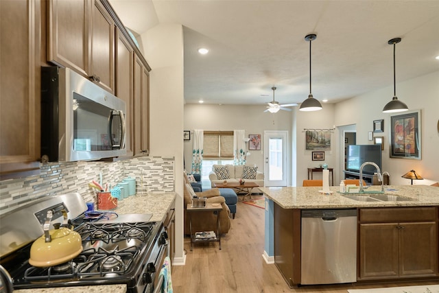 999 Arbor Gln, Conroe, TX 77303 - kitchen with appliances with stainless steel finishes, a sink, open floor plan, light wood-type flooring, and backsplash