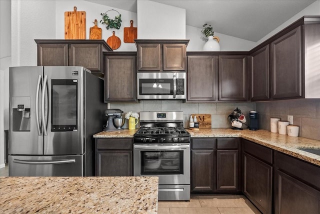 726 Rim Water Dr, Alvin, TX 77511 - kitchen with appliances with stainless steel finishes, dark brown cabinets, tasteful backsplash, vaulted ceiling, and light stone countertops