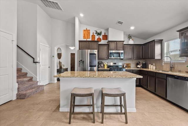 726 Rim Water Dr, Alvin, TX 77511 - kitchen with appliances with stainless steel finishes, a sink, dark brown cabinets, a kitchen island, and a breakfast bar area