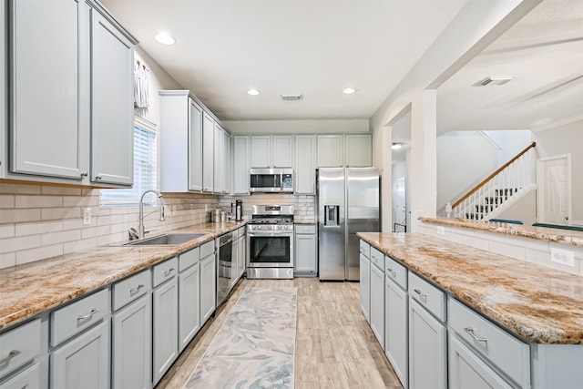 3602 Pine Stream Dr, Pearland, TX 77581 - kitchen featuring appliances with stainless steel finishes, a sink, light wood-type flooring, tasteful backsplash, and gray cabinetry