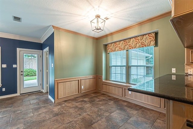 13219 Allysum Ct, Cypress, TX 77429 - unfurnished dining area featuring a chandelier, wainscoting, crown molding, a textured ceiling, and dark stone finish flooring