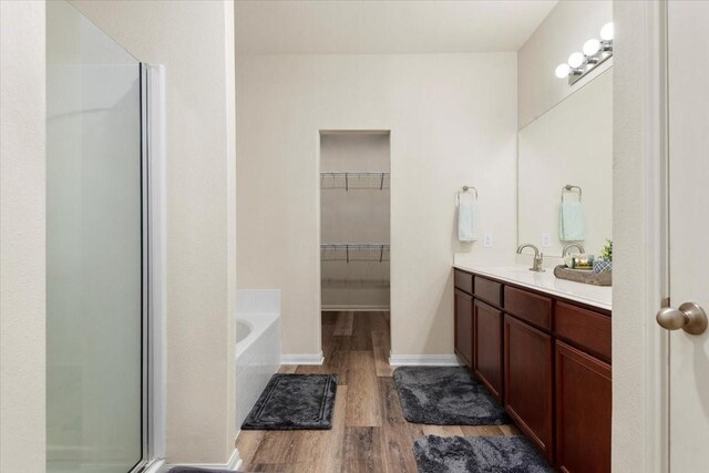 22435 Base Light Dr, Hockley, TX 77447 - full bathroom with wood finished floors, a stall shower, double vanity, a garden tub, and a walk in closet