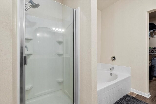 22435 Base Light Dr, Hockley, TX 77447 - full bathroom featuring a stall shower, a garden tub, a walk in closet, and wood finished floors