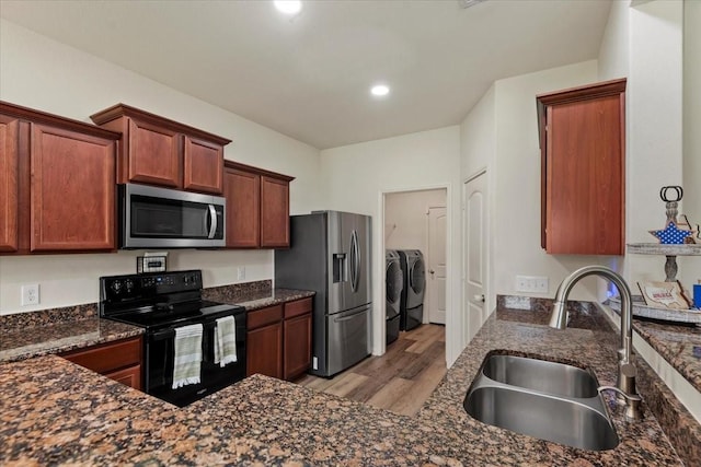22435 Base Light Dr, Hockley, TX 77447 - kitchen featuring appliances with stainless steel finishes, washer and dryer, light wood finished floors, dark stone counters, and recessed lighting